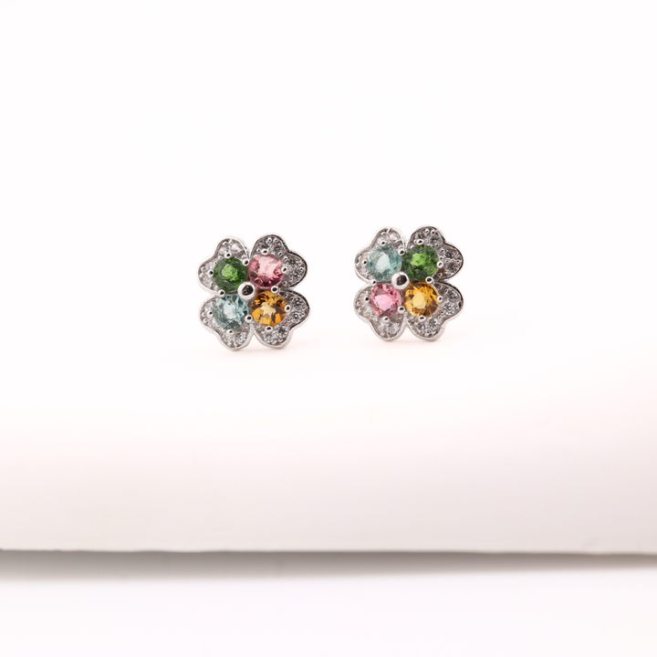 Pair of flower-shaped earrings with Tourmaline gemstones on a white background