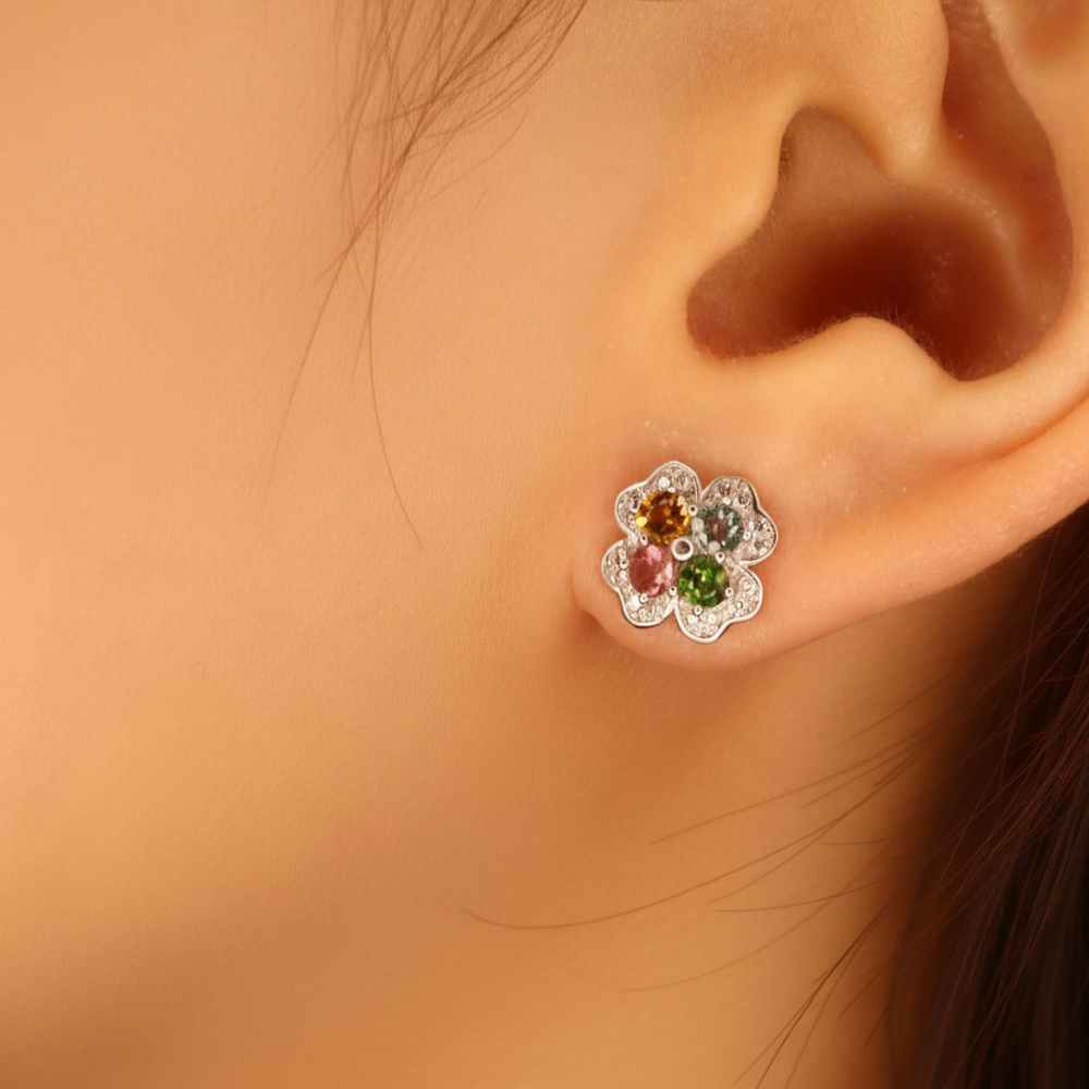 Close-up of an ear wearing a floral earring with Tourmaline gemstones.
